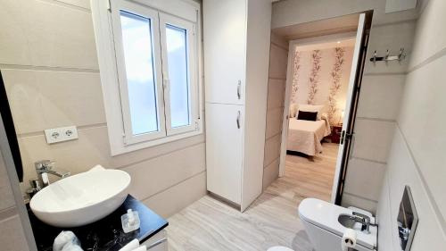 łazienka z umywalką, toaletą i oknem w obiekcie Vivienda Turística Cervantes w mieście Úbeda