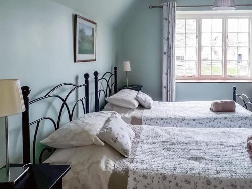 two twin beds in a bedroom with a window at Moorhouse Farm Cottage in Hovingham