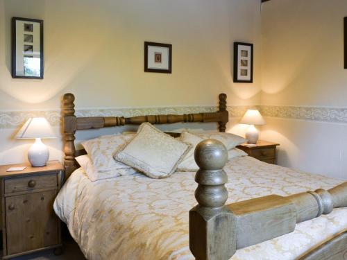 a bedroom with a wooden bed with two lamps at Mews Cottage in Bampton