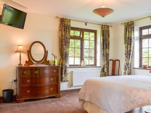 a bedroom with a bed and a mirror and a dresser at Tripp Cottage in Saint Neot
