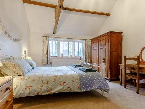 a bedroom with a bed and a desk and a window at Wheelwrights Cottage in Rumburgh