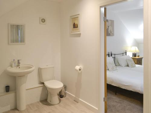 La salle de bains est pourvue d'un lavabo, de toilettes et d'un lit. dans l'établissement Abbey Cottage, à Longhirst