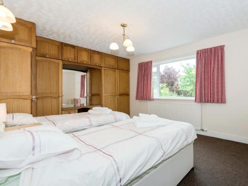 a bedroom with three beds and a window at Oaklands in Langrigg