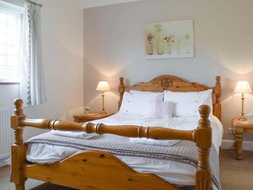 1 dormitorio con cama de madera y almohadas blancas en Kingshill Farm Cottage - 28270 en Great Missenden