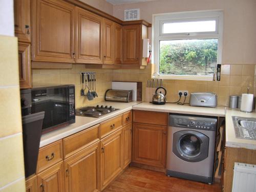 a kitchen with wooden cabinets and a washing machine at Shore Cottage in Silverdale
