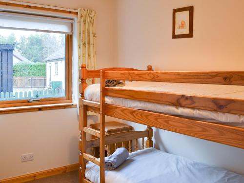 a bedroom with two bunk beds and a window at Cotterton Beag in Nethy Bridge