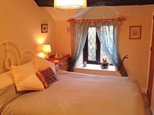 um quarto com uma grande cama branca e uma janela em Hidden Cottage em Spark Bridge
