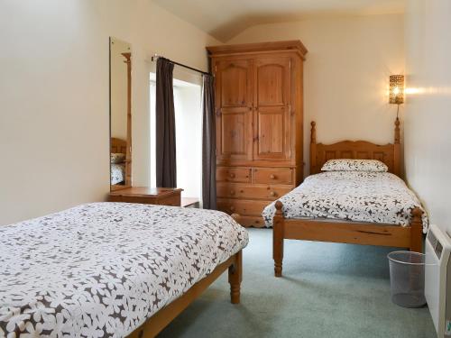 a bedroom with two beds and a dresser at Llofft Yr Yd - 16984 in Brynsiencyn