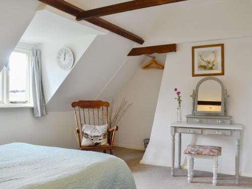 a bedroom with a bed and a chair and a mirror at Three Ash Cottage in Bungay
