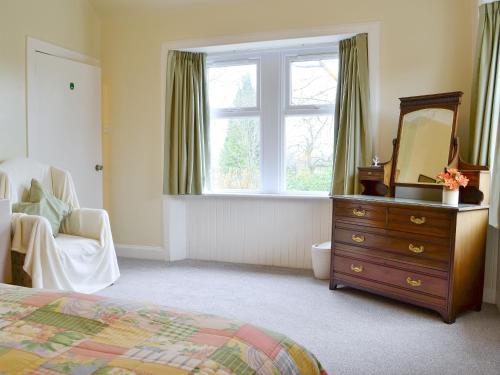 1 dormitorio con tocador, espejo y ventana en Blairhosh Cottage, en Balloch