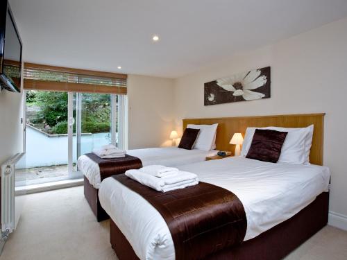 a bedroom with two beds and a large window at The Cottage - Goodrington Lodge in Paignton