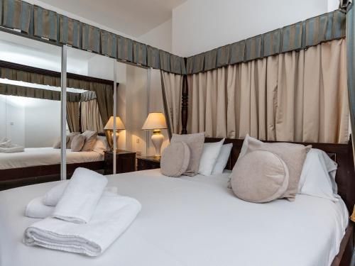a bedroom with a white bed with pillows and a mirror at Oddicombe, Torquay in Torquay