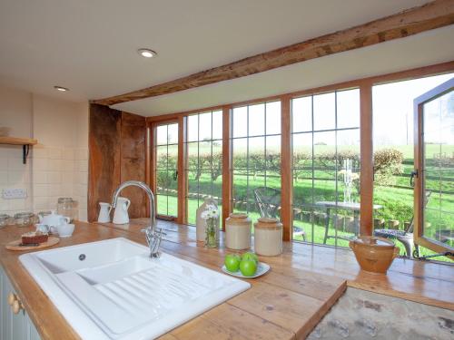 a kitchen with a large white sink and windows at Gittishayne Farm Barn in Colyton