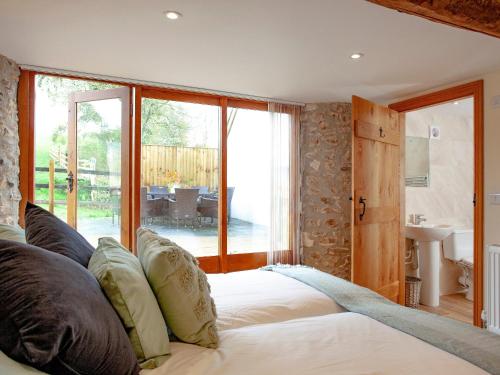 a bedroom with a large bed with a large window at Gittishayne Farm Barn in Colyton