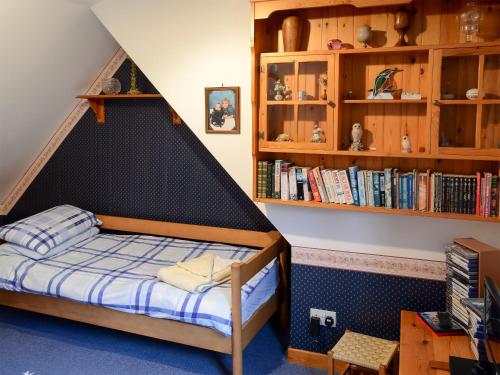 a bed in a room with a book shelf at Culcharry Cottage in Cawdor