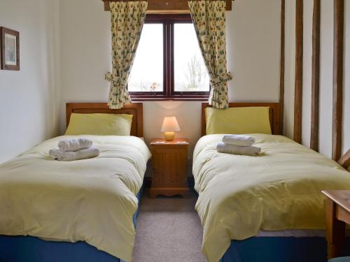 two beds in a small room with a window at Pond Cottage in Peasmarsh