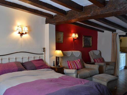 a bedroom with a bed and two chairs at Tudor Cottage Studio in Romsey