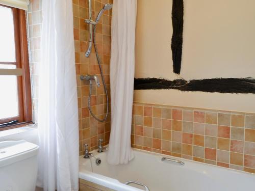 a bathroom with a shower and a bath tub at Tudor Cottage Studio in Romsey