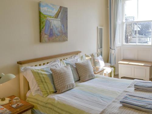 a bedroom with a bed with pillows and a painting on the wall at Grosvenor Cottage in Alnmouth