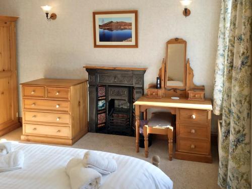 1 dormitorio con cama, escritorio y espejo en Glenmore Cottage, en Ambleside