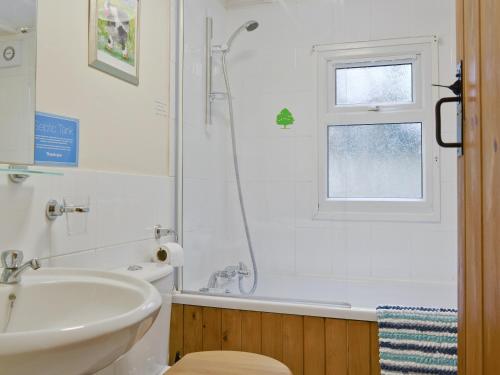 a bathroom with a sink and a tub and a window at The Summer House in Easthope
