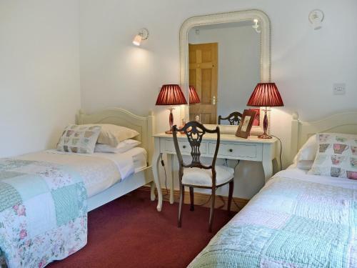 a bedroom with two beds and a desk with a mirror at New Park Farm - Church Cottage in Ireby