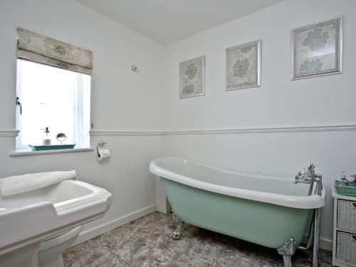 a white bathroom with a tub and a sink at Littlecot in Wyke Regis