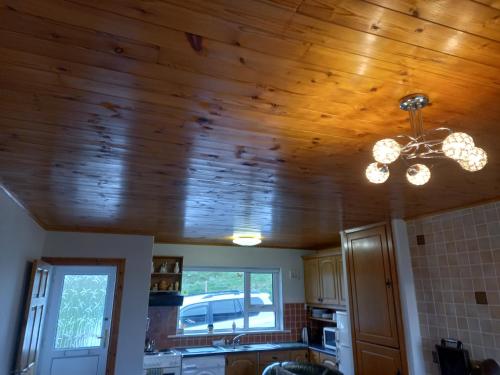 cocina con techo de madera y lámpara de araña en Maggie's House, en Glenties