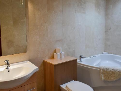 a bathroom with a tub and a toilet and a sink at Wood Cottage in Whaley Bridge