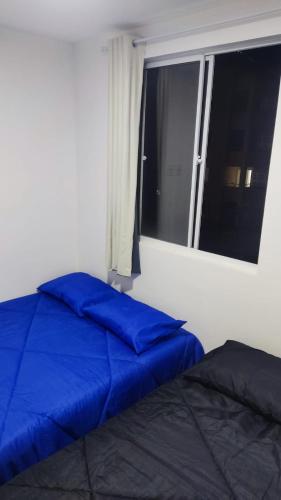 a bed with blue pillows in a room with a window at Mirantes caminho do mar in Parnamirim