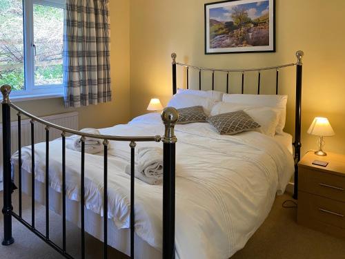 een slaapkamer met een zwart bed met witte lakens en kussens bij High Fellside in Ambleside