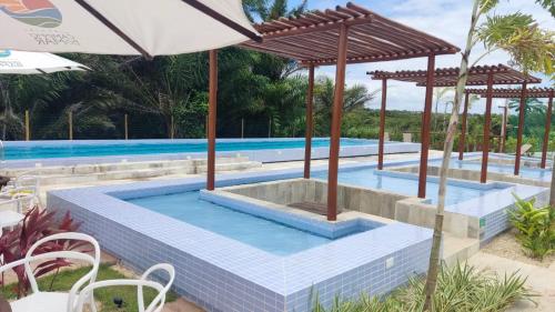 a swimming pool with an umbrella next to a pool at Mirantes caminho do mar in Parnamirim