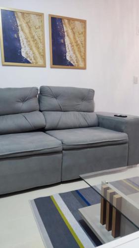 a blue couch in a living room with two pictures at Mirantes caminho do mar in Parnamirim