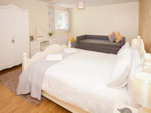 a white bedroom with a large white bed and a couch at Arden Cottage in Twynholm