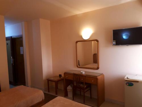 a hotel room with a desk and a mirror at New Pola Hotel in Luxor