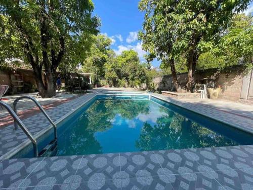 a swimming pool with blue water and some trees at Casa Capistrano in Iguala de la Independencia