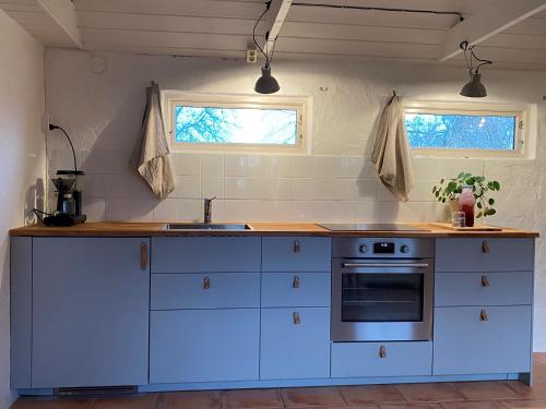 eine Küche mit weißen Schränken, einer Spüle und einem Herd in der Unterkunft BRICK Österlen in Simrishamn