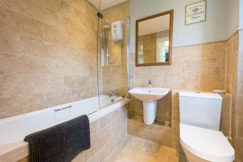 a bathroom with a sink and a toilet and a bath tub at Ploughmans Cottage, St Florence, Tenby in Saint Florence