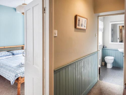 a bathroom with a bed and a toilet in a room at Coastguard Cottage in Fleetwood