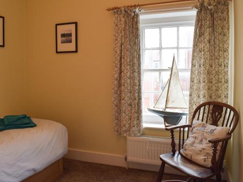 a bedroom with a bed and a window with a toy boat on a desk at Coastguard Cottage in Fleetwood