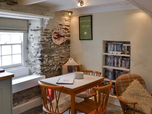 a dining room with a table and chairs and a book shelf at Haven Cottage - 28269 in Port Isaac