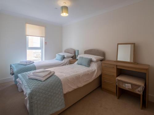1 dormitorio con 2 camas, tocador y espejo en Culver View en Shanklin