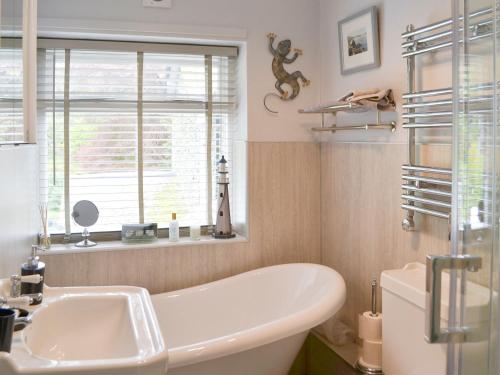 a bathroom with a tub and a sink and a window at The Old Coach House in Thornton