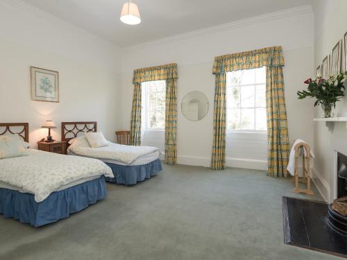 a bedroom with two beds and two windows at The Old Butlers House in Cley next the Sea