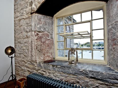 una finestra in un muro di mattoni con un bollitore su una panca di The Sail Loft - Royal William Yard a Millbrook