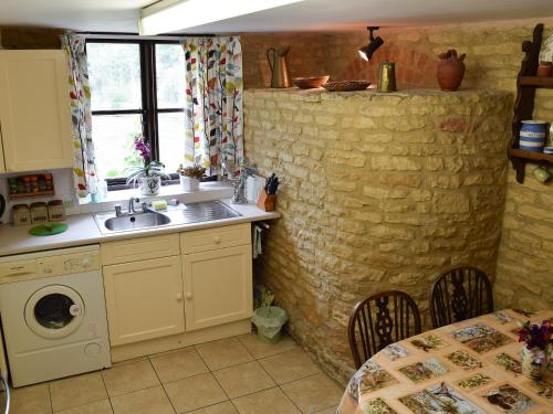 a kitchen with a sink and a washing machine at Picket Piece Cottage in Chadlington