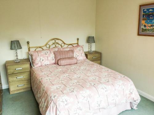 a bedroom with a pink bed with two night stands at Trewithen Farm Bungalow in St Merryn