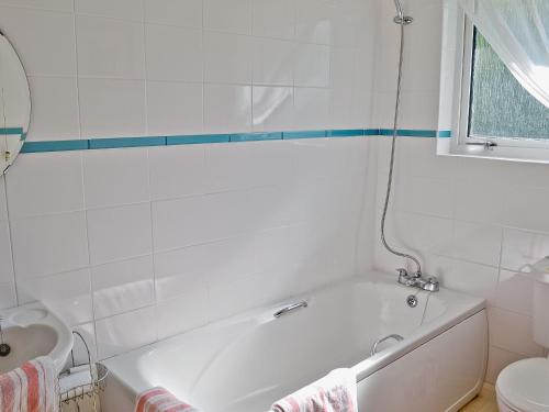a white bathroom with a tub and a sink at Trewithen Farm Bungalow in St Merryn