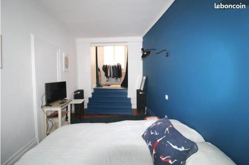a bedroom with a bed with a blue wall and stairs at Chez Samuel à Dieppe in Dieppe