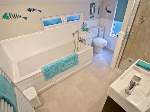 a bathroom with a tub and a toilet and a sink at Kerensa in Looe